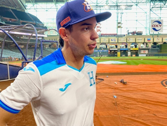 Astros player Mauricio Dubón talks to media during batting practice while wearing a Honduran men's soccer team jersey