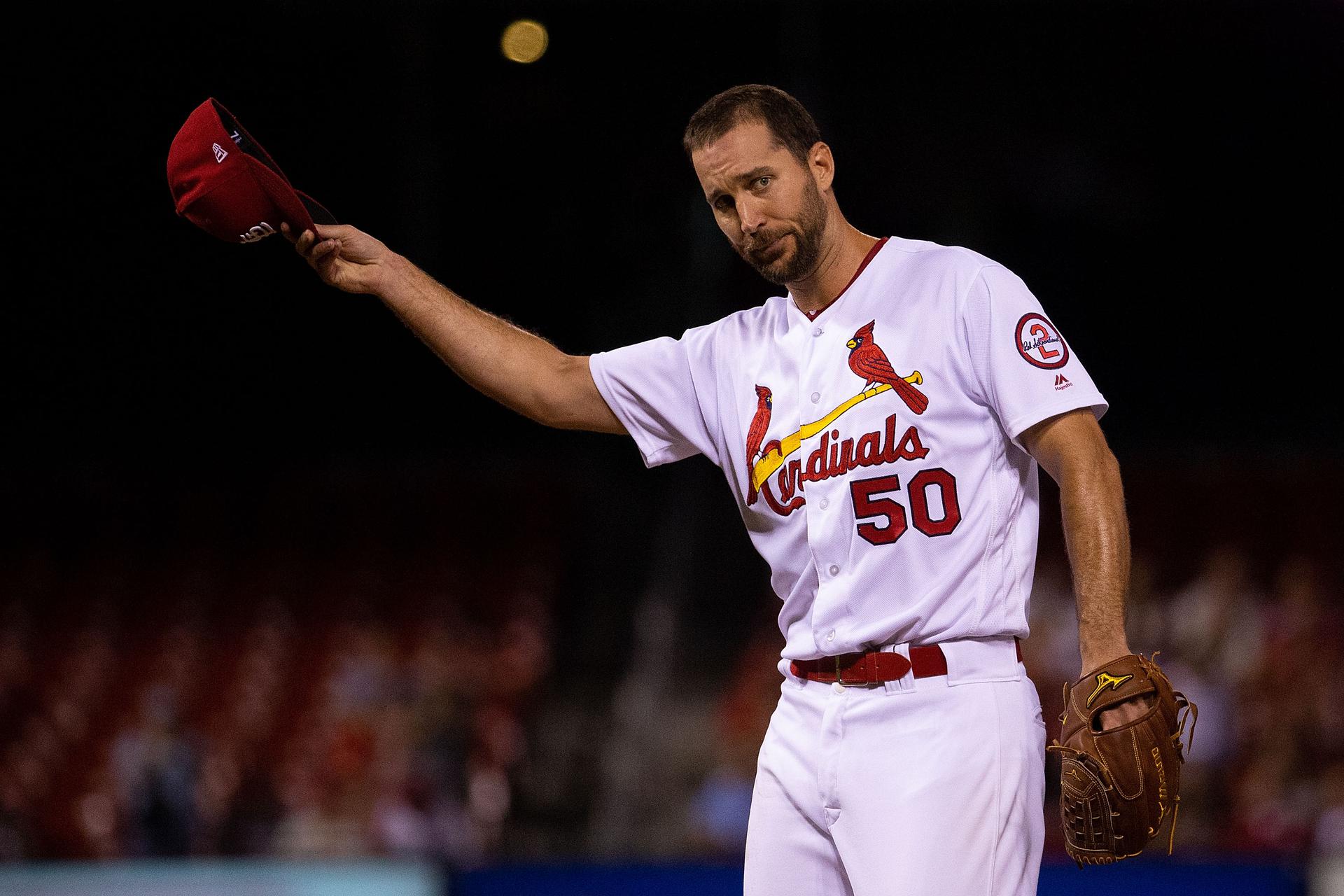 Cardinals pitcher Adam Wainwright tips his hat to the crowd while wearing a white jersey