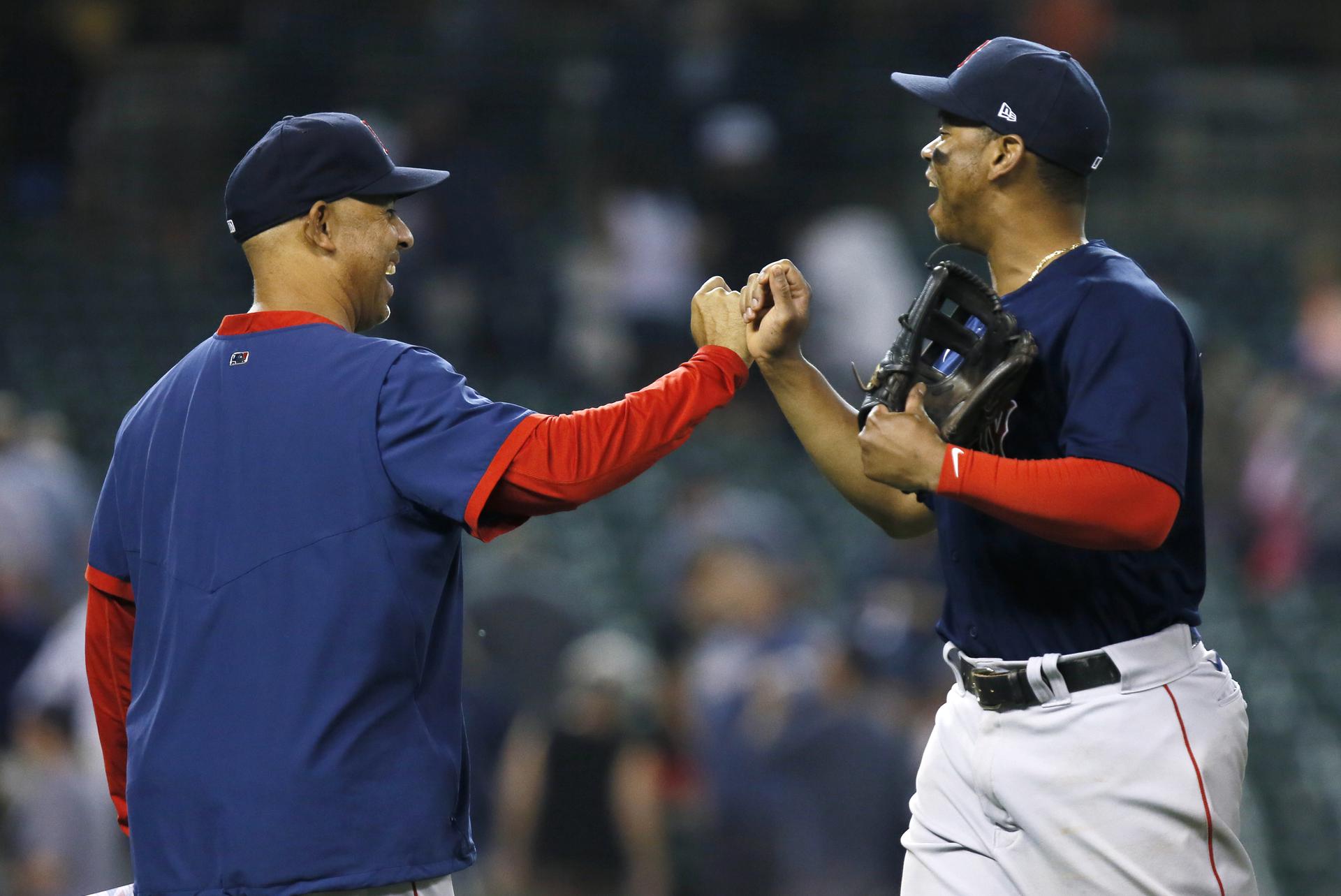 Red Sox manager Alex Cora (left) fist bumps with Red Sox third baseman Rafael Devers (right)