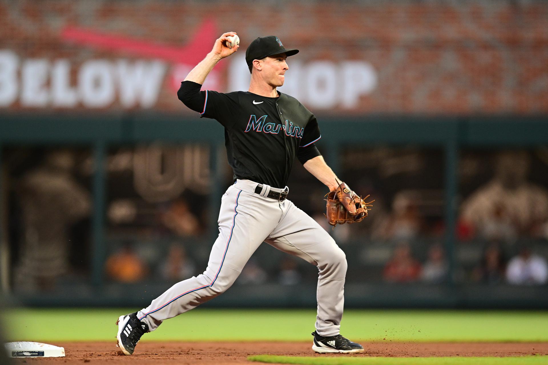Joey Wendle throws a baseball from the infield while wearing a black Marlins jersey