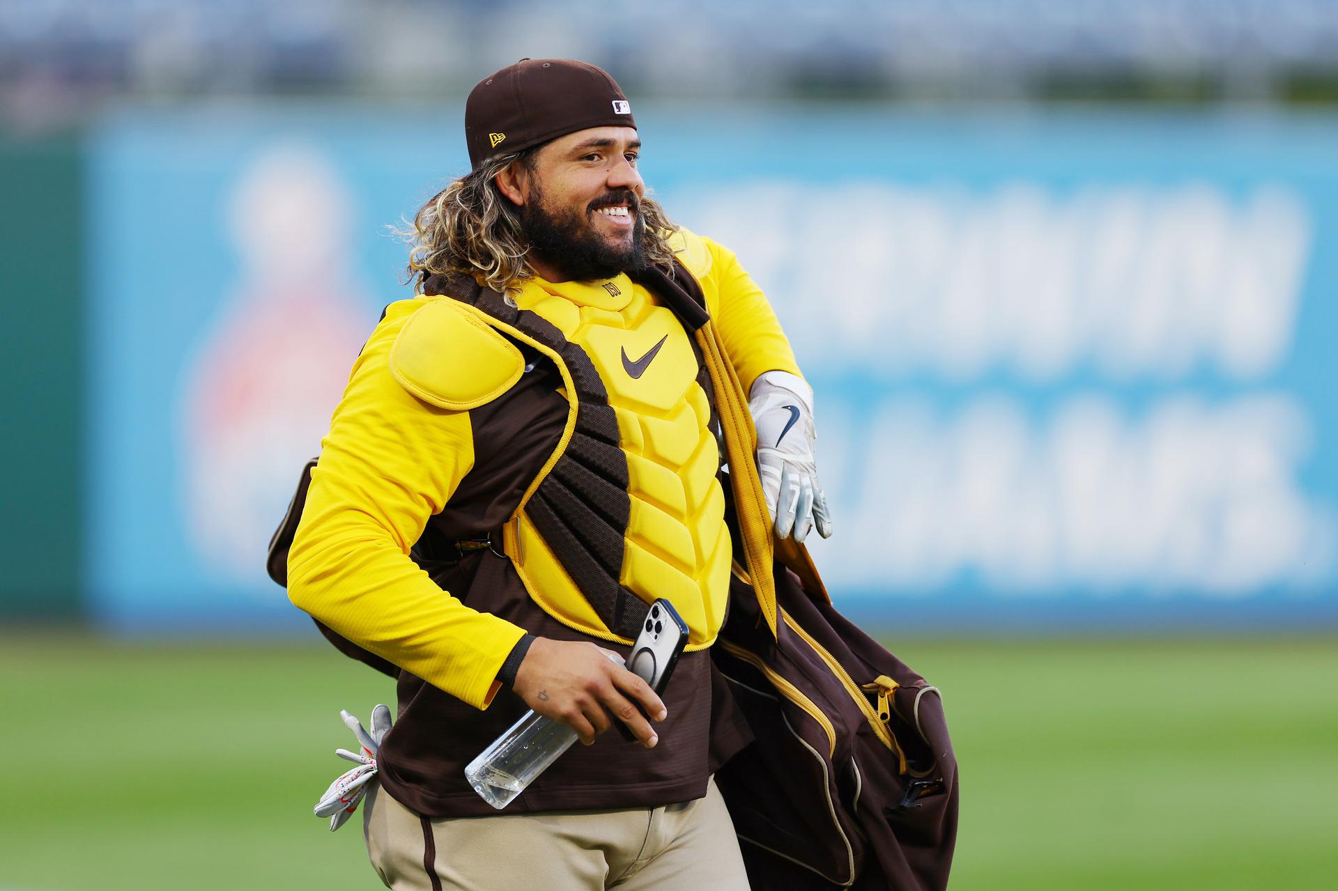 Jorge Alfaro walks across the field wearing his catcher gear and carrying a baseball bag