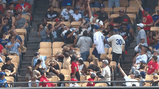 An animated gif of a dad catching a foul ball with a baby on his chest