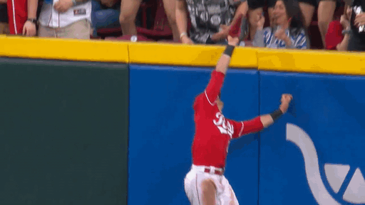 An animated gif of TJ Friedl making a leaping catch at the fence