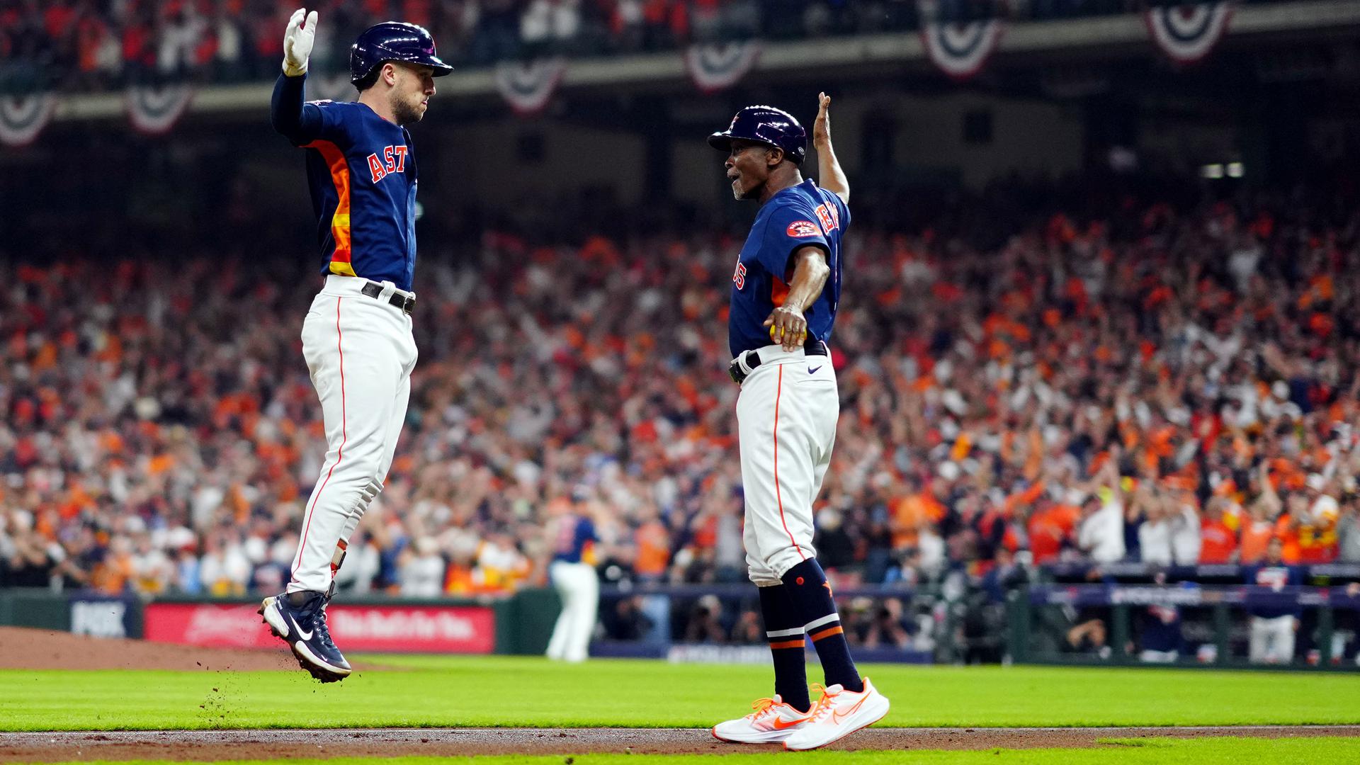 Alex Bregman leaps in the air, hand extended, ready to high-five the Astro's third-base coach, who waits with his arm extended