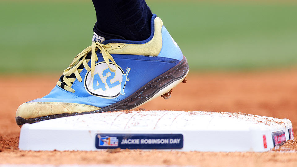 A cleat with the number 42 on it is shown stepping on a base with a Jackie Robinson Day plate on it.