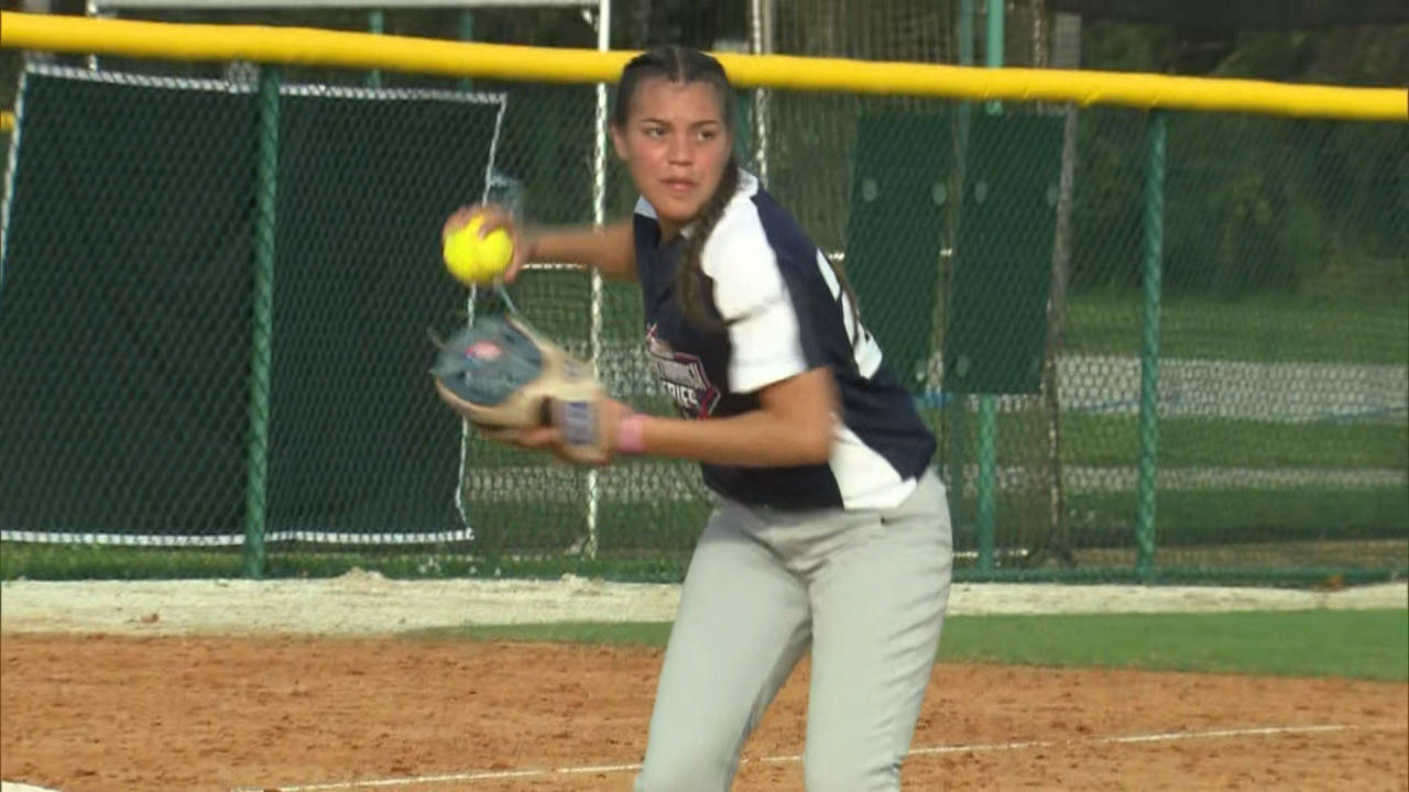 A softball player prepares to throw the ball to first base