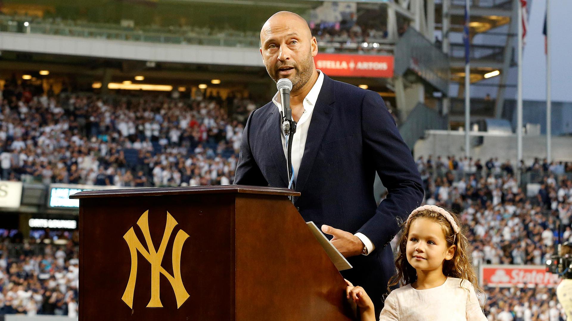 Derek Jeter speaks at a podium with his daughter standing beside him