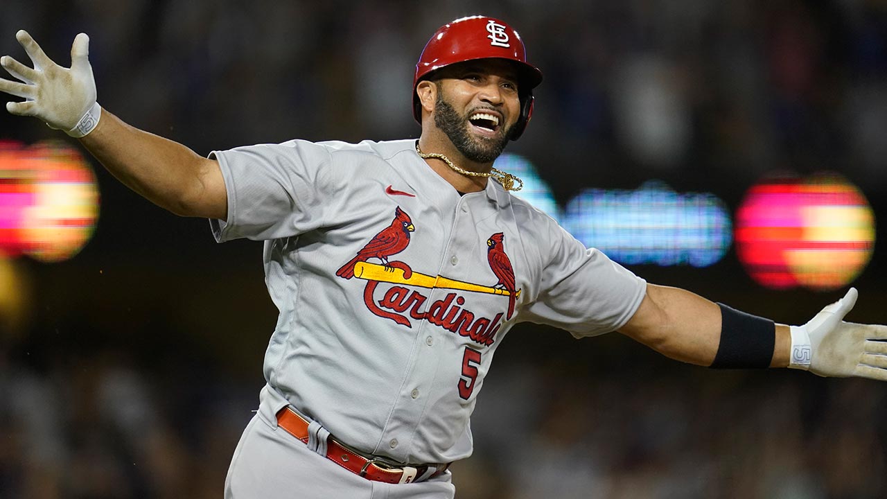Albert Pujols raises his arms while rounding the bases after hitting his 700th career home run