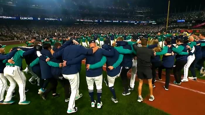 Mariners players dance on the field after clinching a postseason berth